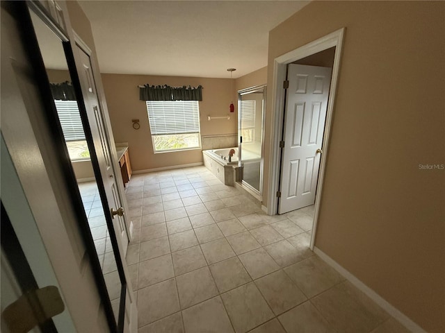 bathroom with a shower stall, baseboards, a bath, and tile patterned floors