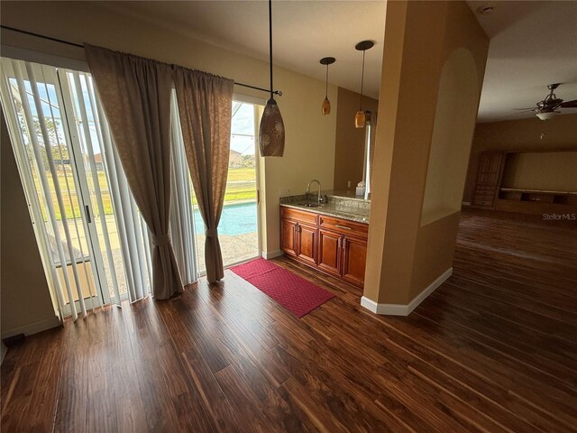 kitchen featuring dark wood-style flooring, brown cabinets, baseboards, and light stone countertops