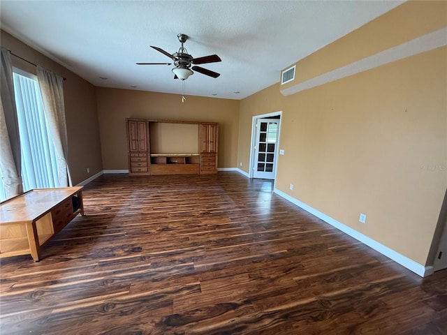 unfurnished living room with baseboards, visible vents, a ceiling fan, dark wood-style floors, and a textured ceiling