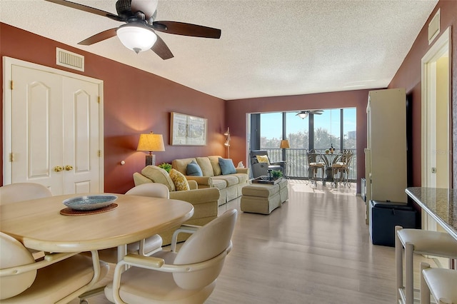 living area featuring ceiling fan, a textured ceiling, and light wood-style floors