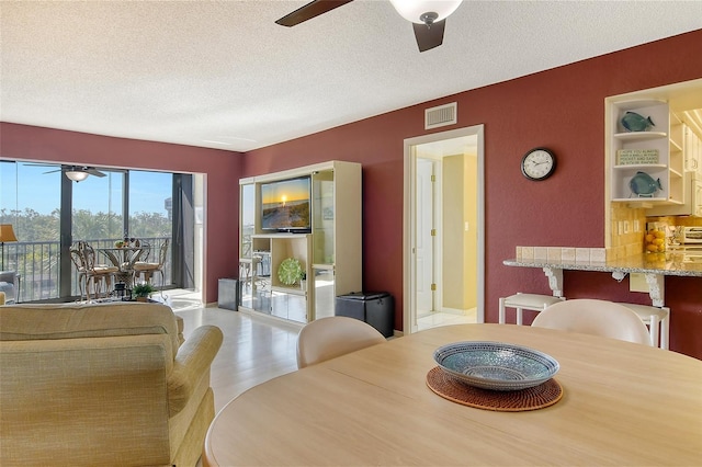 dining space featuring a ceiling fan, a textured ceiling, and wood finished floors