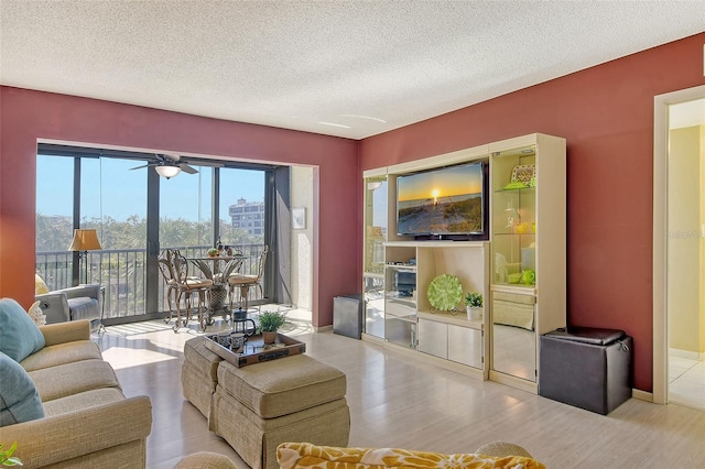 living room with wood finished floors, a textured ceiling, a ceiling fan, and baseboards