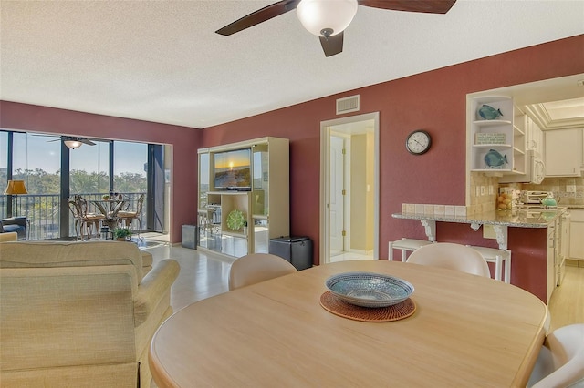dining area with a ceiling fan, a textured ceiling, and wood finished floors
