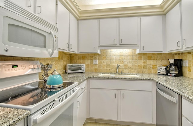 kitchen with white appliances, a sink, white cabinets, and decorative backsplash