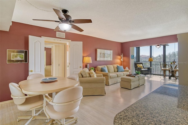 living area featuring a textured ceiling, light wood-style flooring, and a ceiling fan