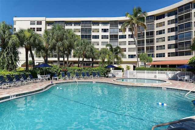 community pool with a patio area and fence
