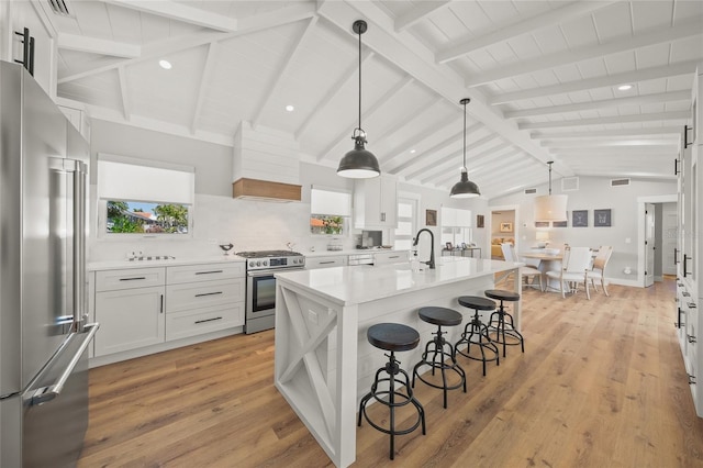 kitchen featuring a kitchen bar, light wood-style flooring, lofted ceiling with beams, appliances with stainless steel finishes, and light countertops