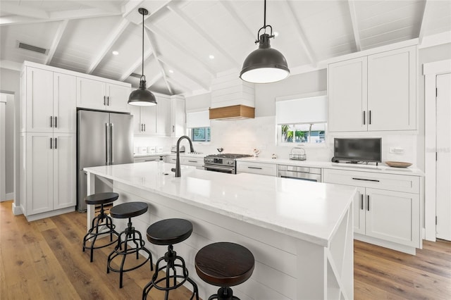 kitchen featuring premium appliances, white cabinetry, and lofted ceiling with beams