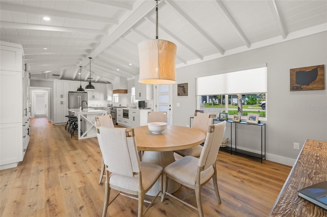 dining space featuring baseboards, vaulted ceiling with beams, and light wood finished floors