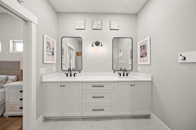 ensuite bathroom with double vanity, ensuite bath, baseboards, and a sink