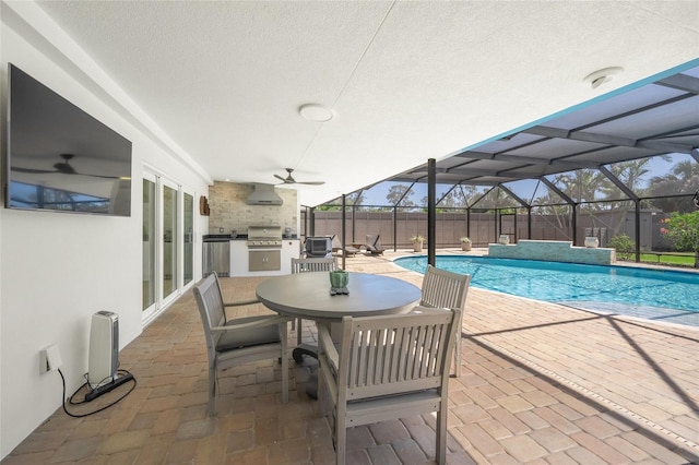 outdoor pool with glass enclosure, a patio, exterior kitchen, and a ceiling fan