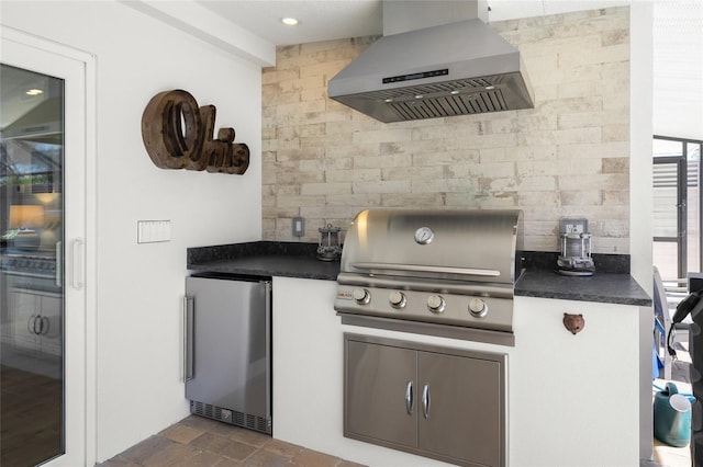 kitchen with freestanding refrigerator, decorative backsplash, dark countertops, and wall chimney exhaust hood