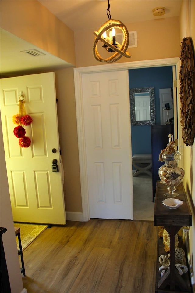 foyer featuring visible vents, baseboards, and wood finished floors