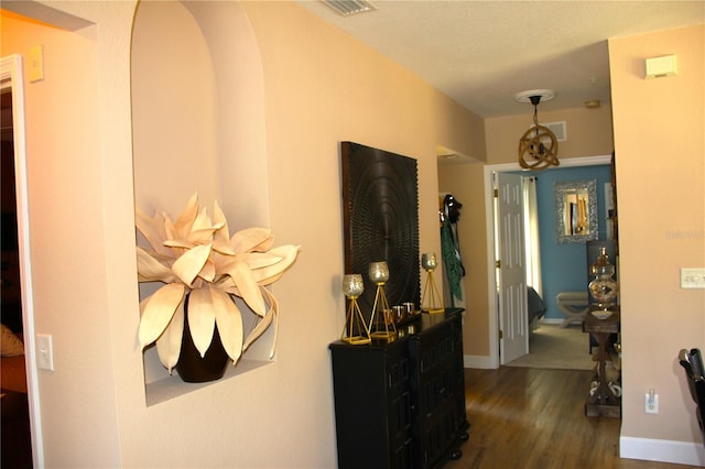 hallway featuring dark wood-style floors, visible vents, and baseboards