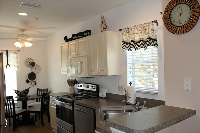 kitchen featuring dark countertops, white microwave, stainless steel electric range oven, dishwashing machine, and a sink