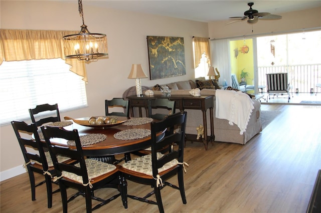 dining room featuring light wood finished floors, baseboards, and ceiling fan with notable chandelier