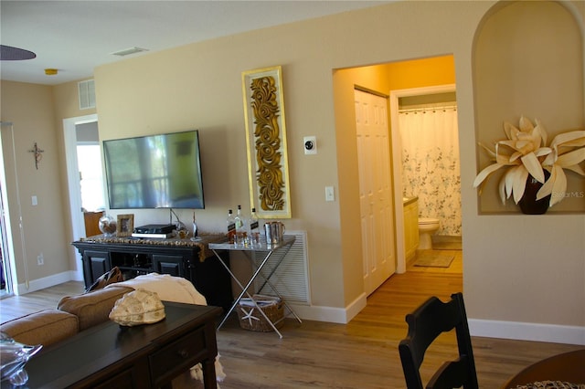 living room with visible vents, baseboards, and wood finished floors