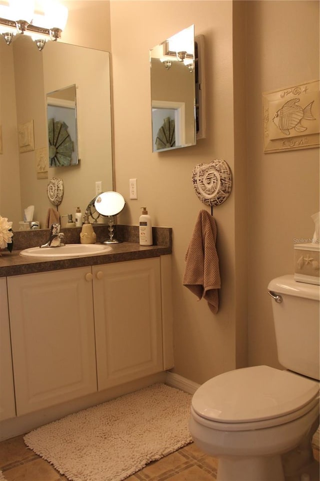 bathroom featuring tile patterned flooring, toilet, a notable chandelier, vanity, and baseboards