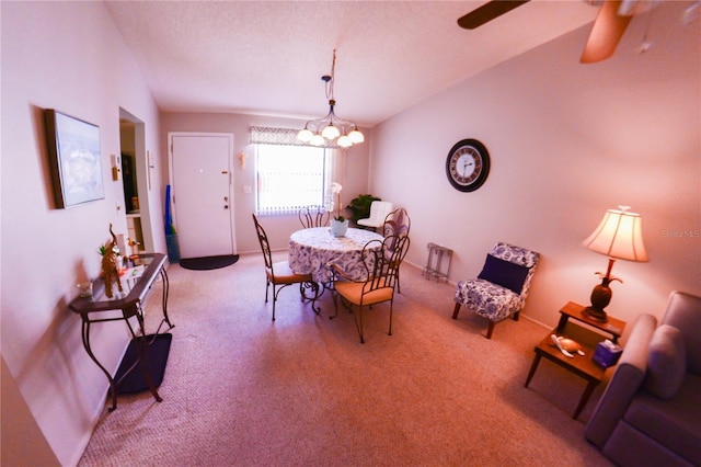 carpeted dining area featuring vaulted ceiling and ceiling fan with notable chandelier