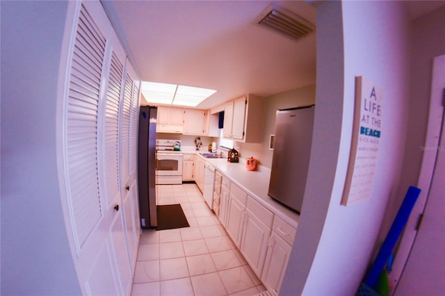 kitchen with a sink, white cabinetry, white appliances, light countertops, and light tile patterned floors