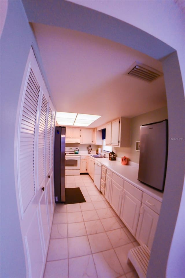 kitchen featuring visible vents, white appliances, white cabinets, light countertops, and light tile patterned floors