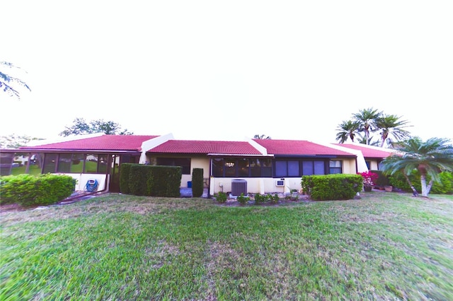 view of front of house with a front yard, central air condition unit, a tile roof, and a sunroom