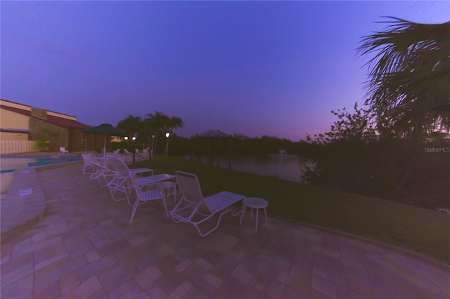 patio terrace at dusk featuring an outdoor pool