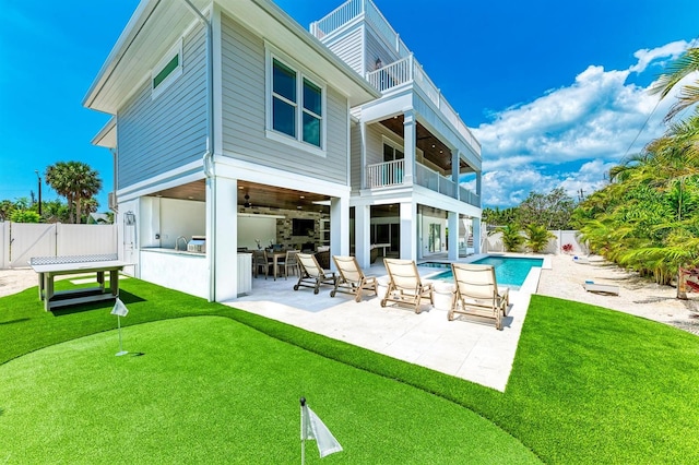 back of property with a fenced in pool, a balcony, outdoor dry bar, and a patio area