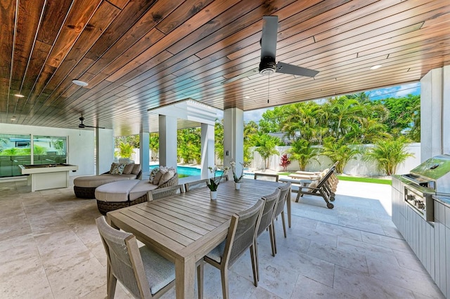 view of patio / terrace featuring an outdoor living space, exterior kitchen, outdoor dining area, a fenced backyard, and a ceiling fan