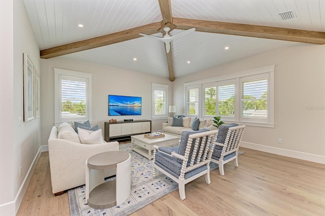 living area featuring light wood-type flooring, visible vents, a ceiling fan, baseboards, and vaulted ceiling with beams