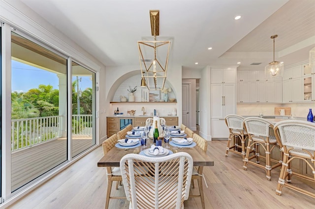 dining area featuring light wood finished floors, recessed lighting, and arched walkways