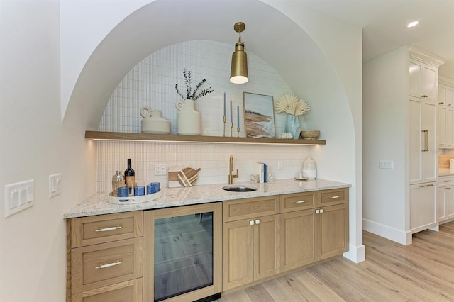 bar featuring beverage cooler, decorative light fixtures, tasteful backsplash, light wood-style floors, and baseboards