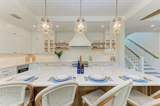 kitchen with premium range hood, visible vents, beamed ceiling, open shelves, and decorative light fixtures