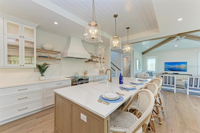 kitchen with custom exhaust hood, stainless steel electric stove, light wood finished floors, and open floor plan