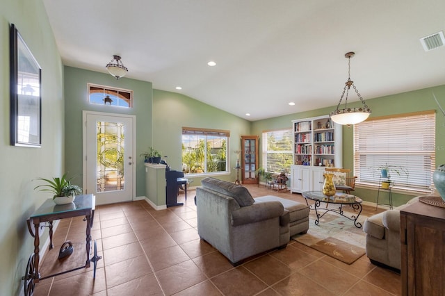 living area featuring vaulted ceiling, dark tile patterned flooring, visible vents, and baseboards