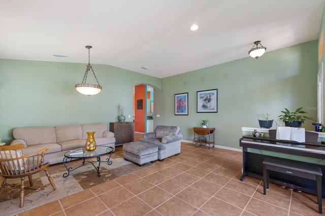 tiled living area with arched walkways, visible vents, vaulted ceiling, and baseboards