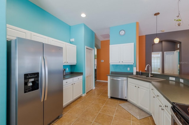 kitchen with appliances with stainless steel finishes, dark countertops, a sink, and white cabinetry