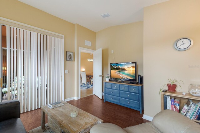 living room featuring dark wood-style flooring, visible vents, and baseboards