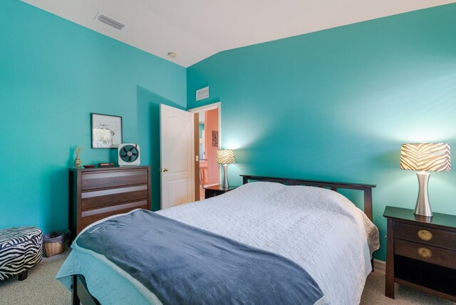 bedroom with visible vents, vaulted ceiling, and carpet flooring