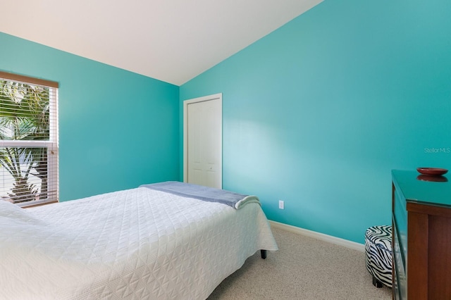 carpeted bedroom with baseboards and vaulted ceiling