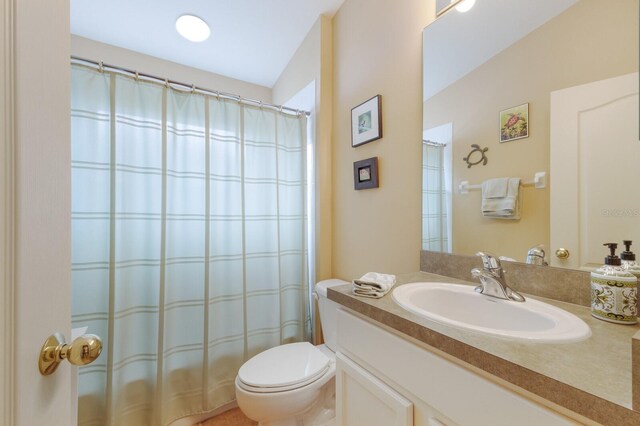 full bath featuring toilet, a shower with shower curtain, and vanity