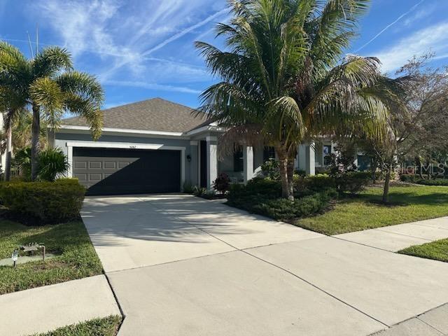 view of front of home with a garage, concrete driveway, and a front lawn