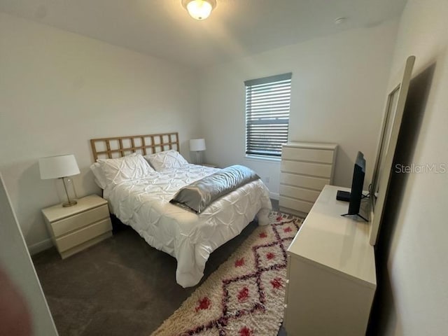 bedroom featuring dark colored carpet and baseboards