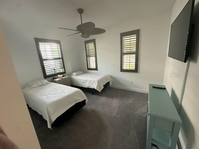 carpeted bedroom featuring multiple windows, a ceiling fan, and baseboards