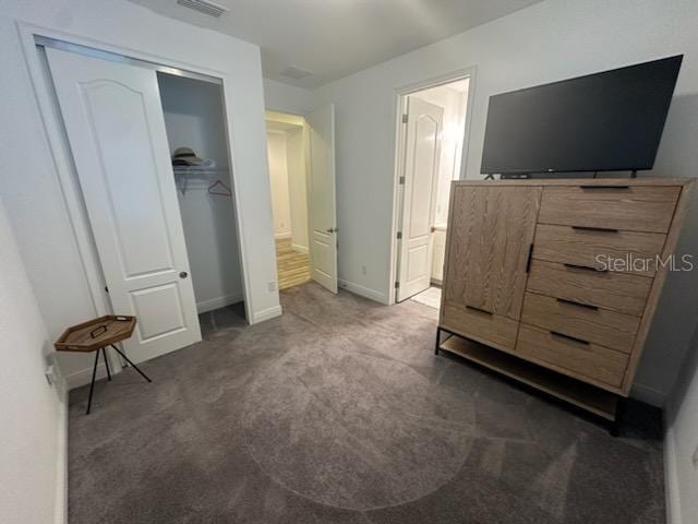 bedroom with a closet, carpet flooring, ensuite bath, and baseboards