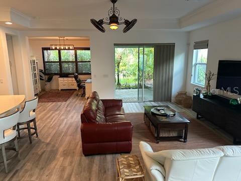 living area featuring ornamental molding, a raised ceiling, and wood finished floors