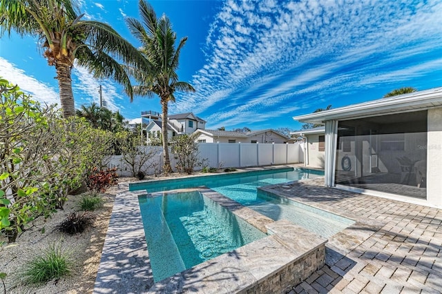 view of pool featuring a patio, a pool with connected hot tub, a fenced backyard, and a sunroom