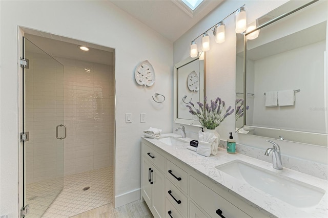 bathroom with double vanity, a skylight, a sink, and a stall shower