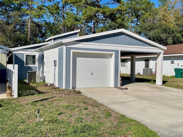 garage with a carport, driveway, and central air condition unit