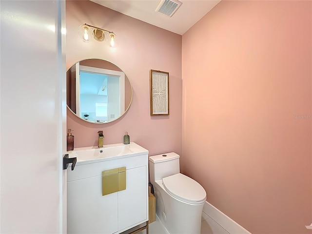 half bath with toilet, vanity, and visible vents